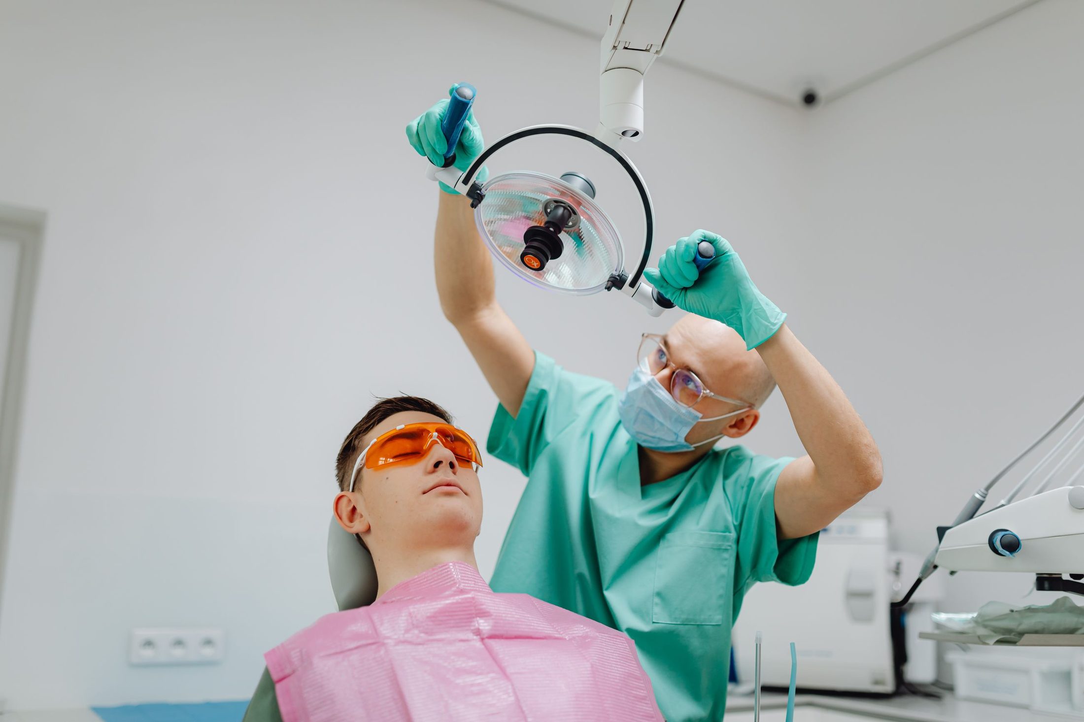 A patient in protective glasses as the dentist adjusts the light