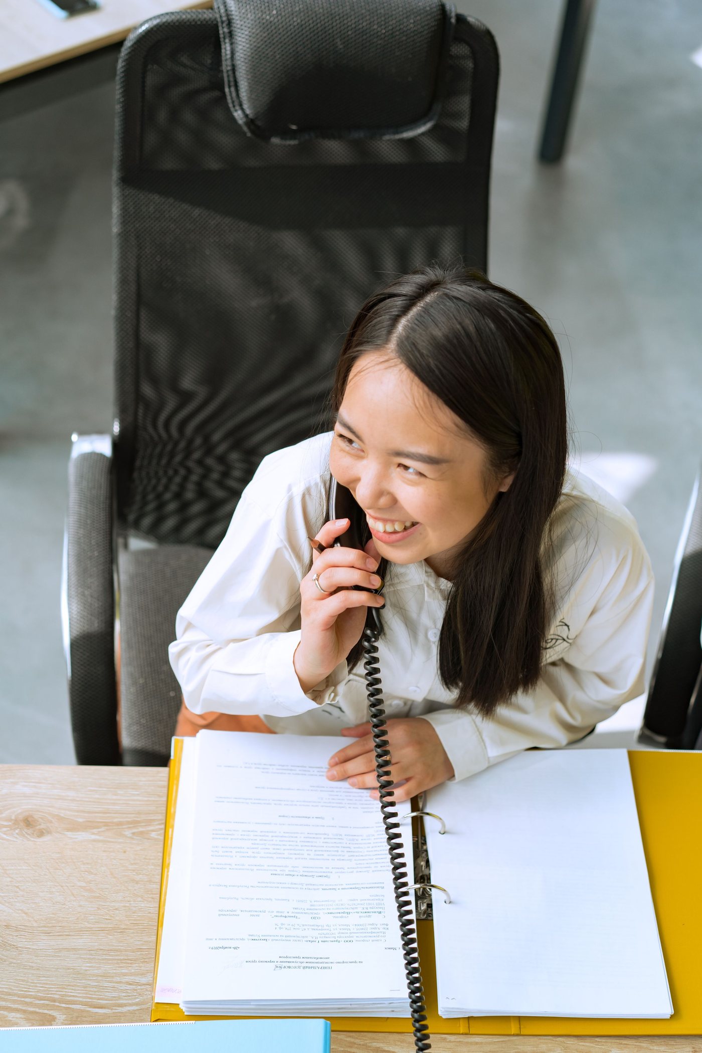 A smiling woman answering the phone at her desk