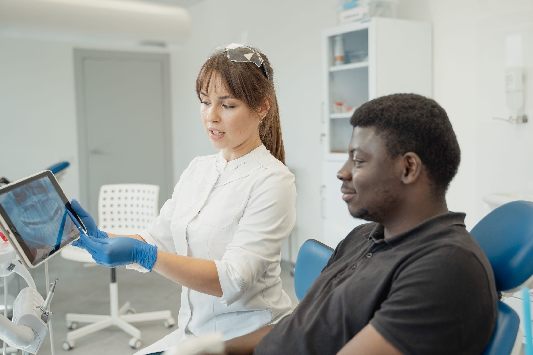A dentist explaining a treatment plan on a tablet to a patient